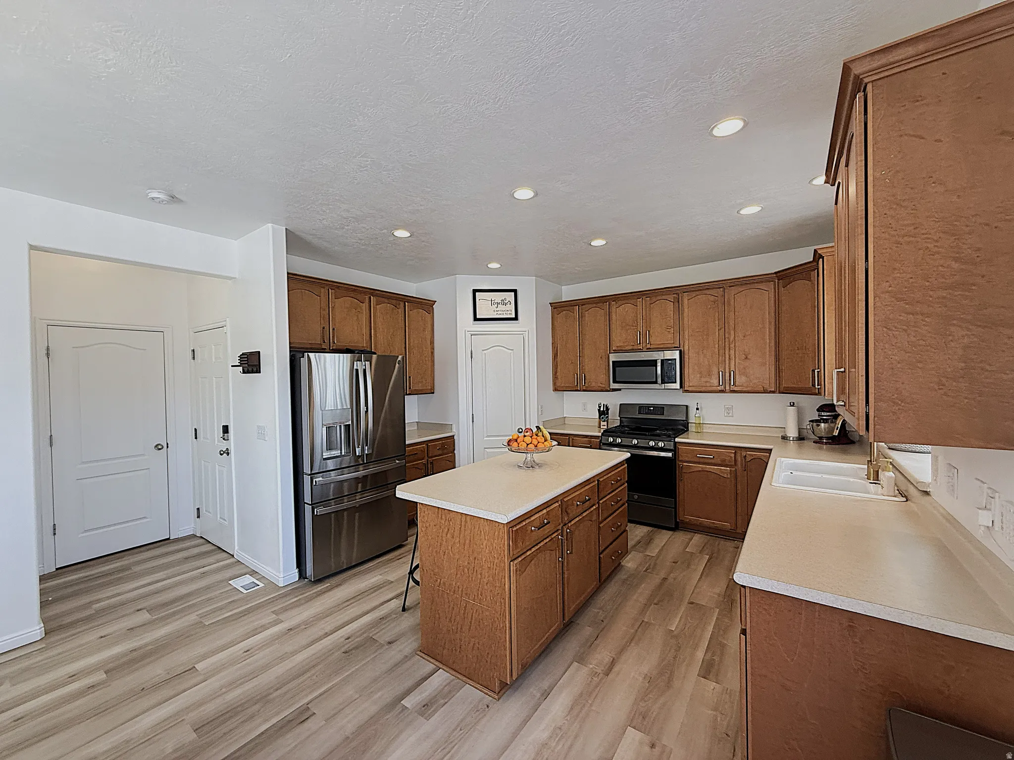 Kitchen featuring wood-finish flooring, recessed lighting, wood cabinetry, stone-finish countertops, and stainless-steel appliances
