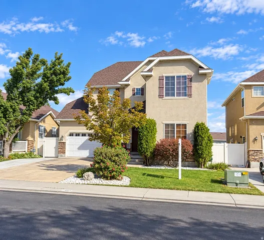 Two-story stucco exterior with decorative shutters, integrated two-car garage, and a concrete driveway