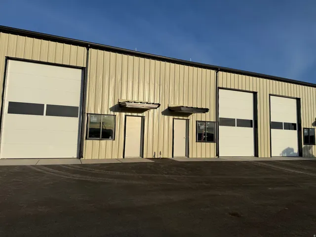 Corrugated metal exterior with multiple bay doors, individual entry doors, and dark-framed windows