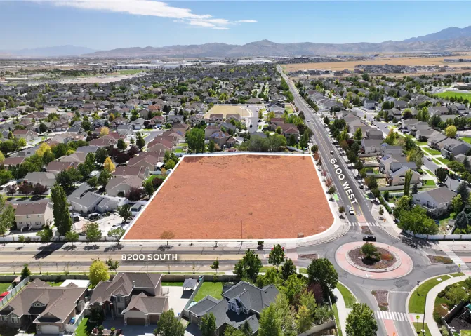 Expansive land parcel featuring road frontage on 6400 West and 8200 South, surrounded by residential development