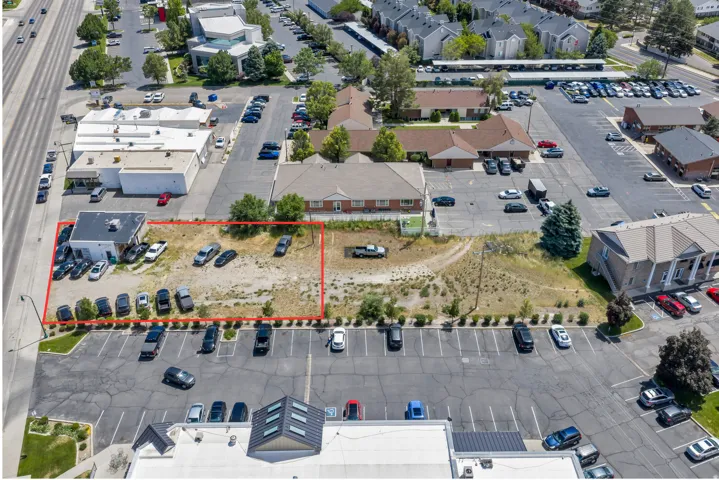 Commercial property featuring a paved parking area, a single-story building with a flat roof, and an expansive undeveloped lot