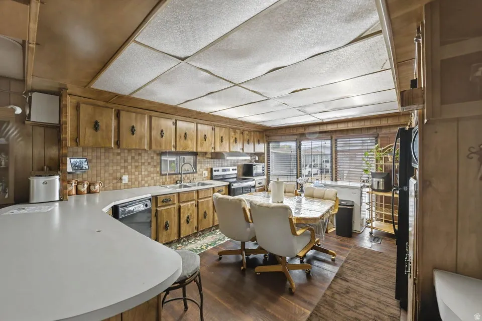 Kitchen featuring wood-finish cabinetry, white countertops, tile backsplash, and wood-finish flooring