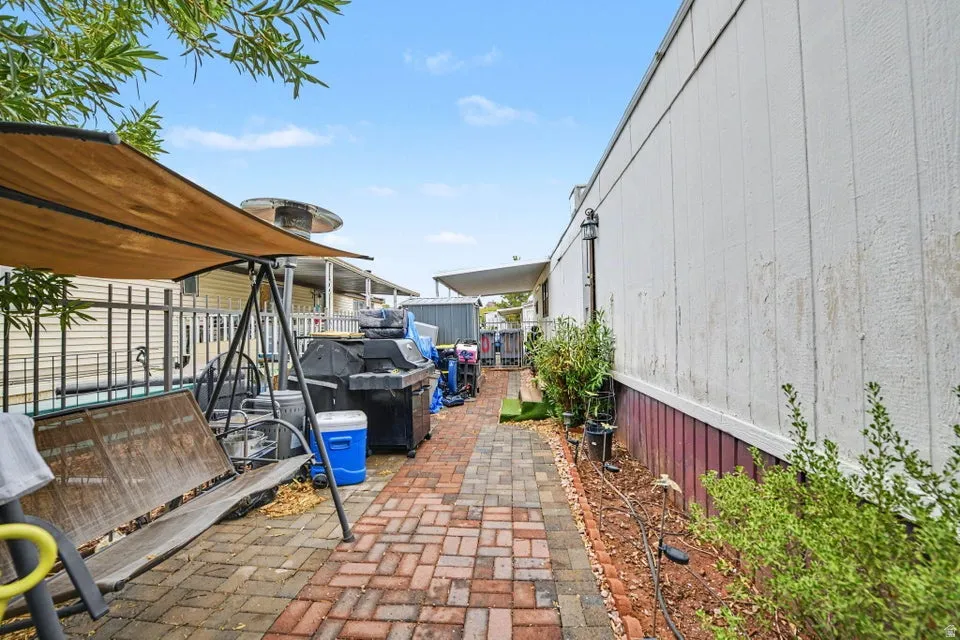 Brick paver pathway with border, perimeter landscaping, and partial fencing