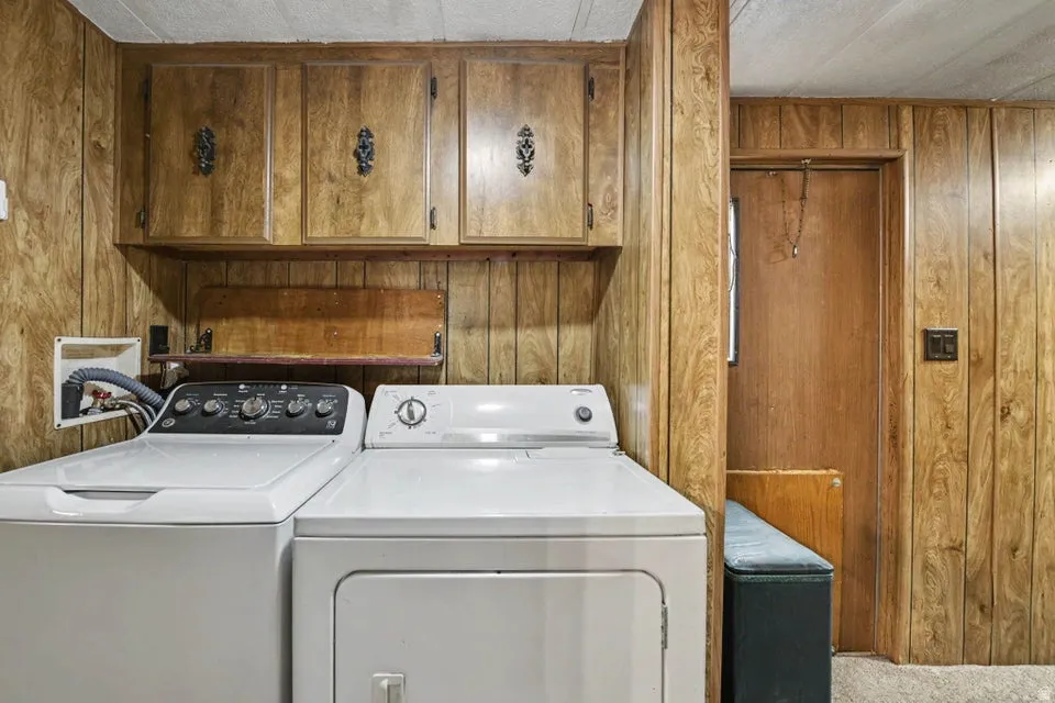 Laundry area with wood-finish paneling, overhead wood-finish cabinetry, and a built-in wooden shelf