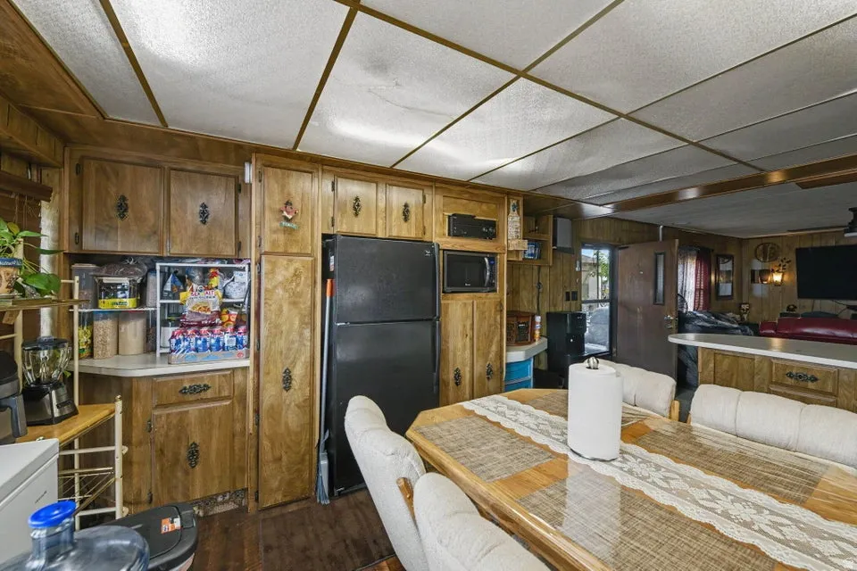 Kitchen featuring wood-finish cabinetry, white countertops, built-in microwave, and a black refrigerator