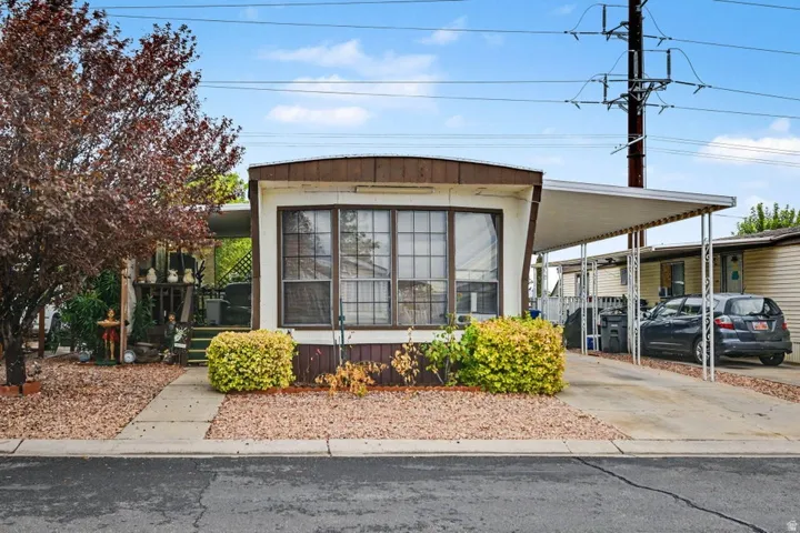 Front exterior with a covered carport, mature landscaping, and a covered porch