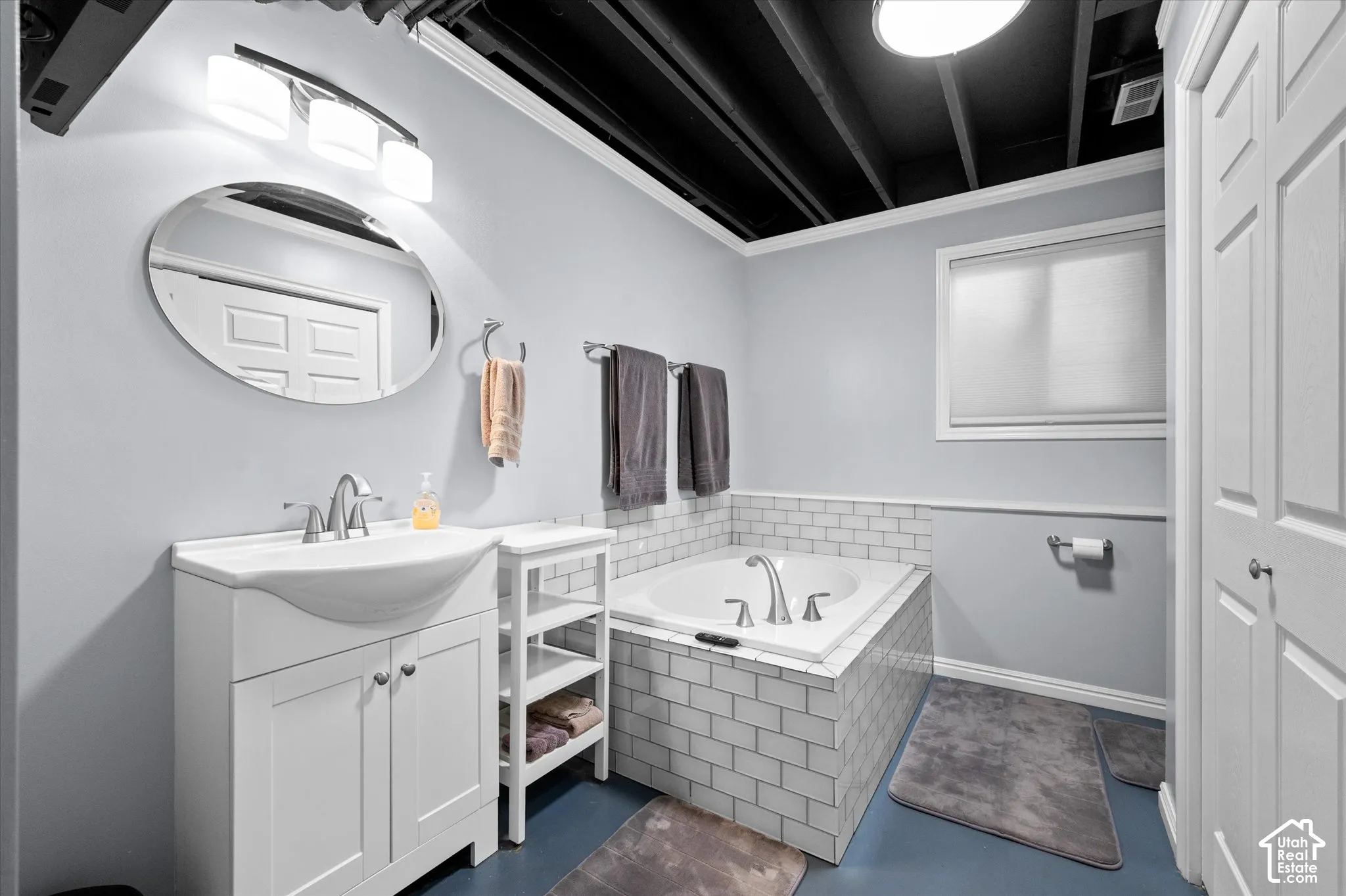 White vanity with integrated sink and chrome fixtures, large soaking tub