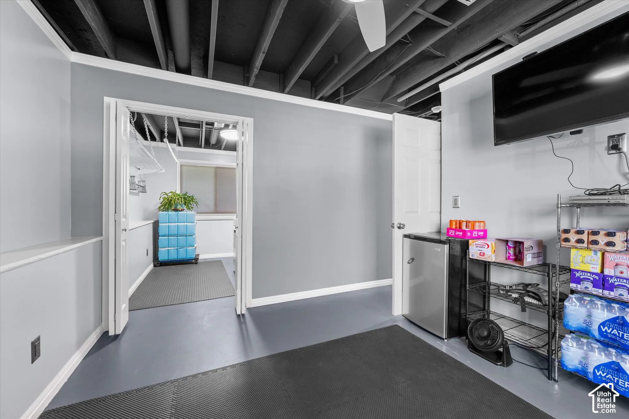 Exposed ceiling beams, painted gray walls, recessed lighting, and a neutral flooring surface