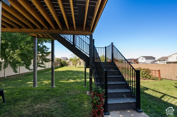 Expansive backyard featuring a manicured lawn, multi-level deck with black railings, and privacy fencing