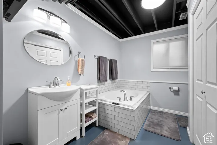 White vanity with integrated sink and chrome fixtures, large soaking tub