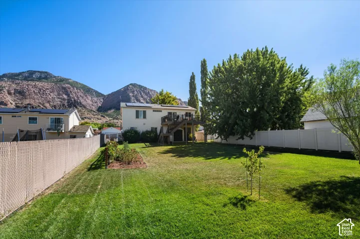 Expansive green lawn with mature trees and a privacy fence