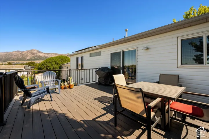 Expansive outdoor deck with mountain scenery, featuring composite decking, black metal railings, white siding, and sliding glass doors
