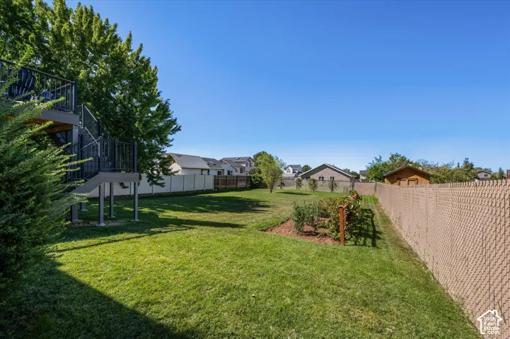 Expansive backyard featuring a manicured lawn, established landscaping, and a multi-level deck with staircase