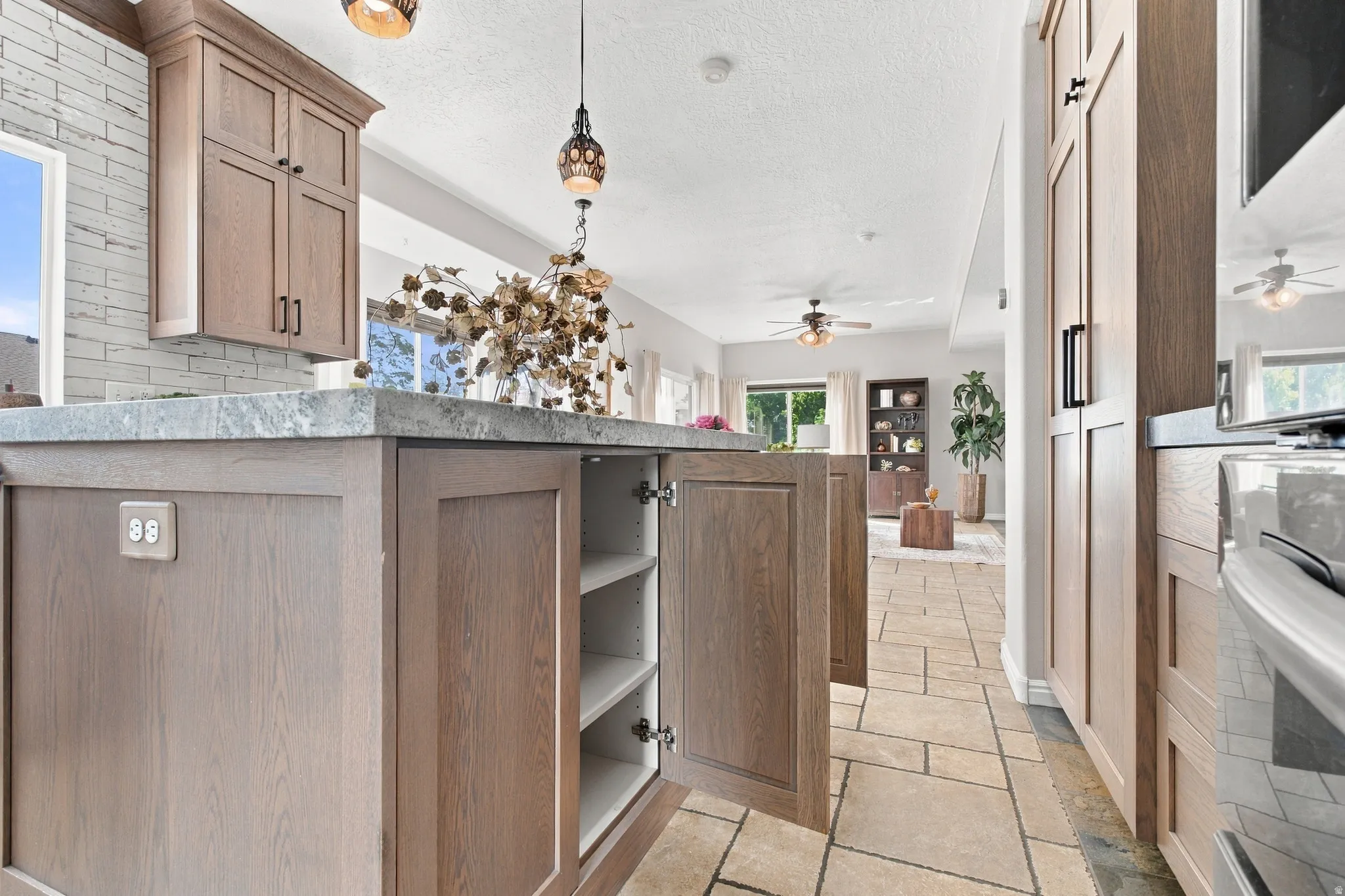 Cabinets with shelves on one side of the island and cabinets, hidden trash and drawers on other side.