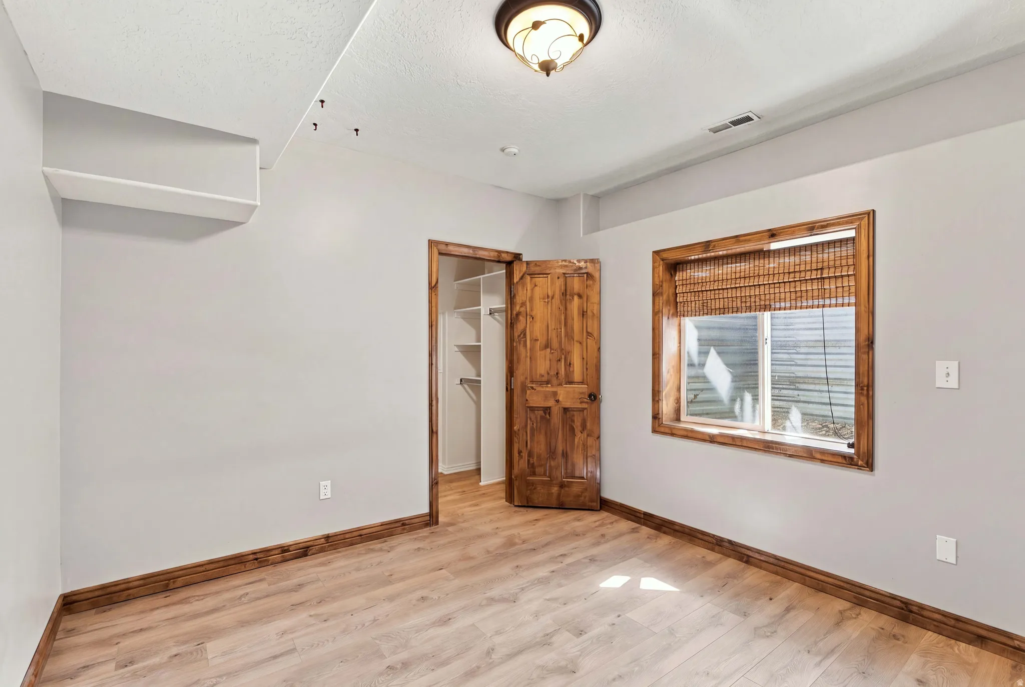 5th bedroom in daylight basement with matching alder door, window and baseboards.  Through closet is the high effenciency furnace and large crawl space storage.