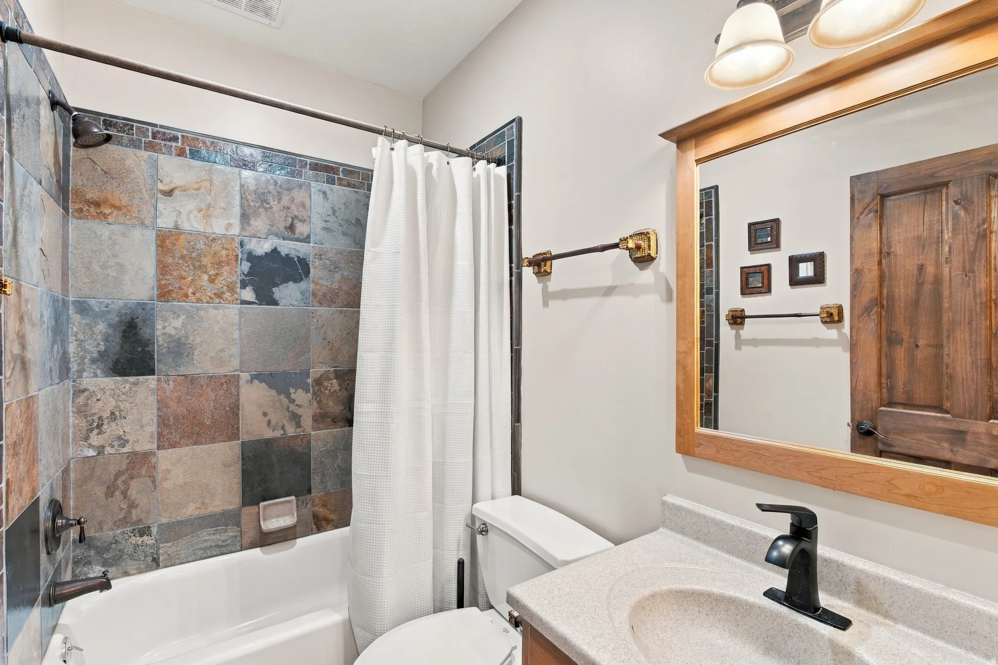 Tub-shower combination with natural stone tile.