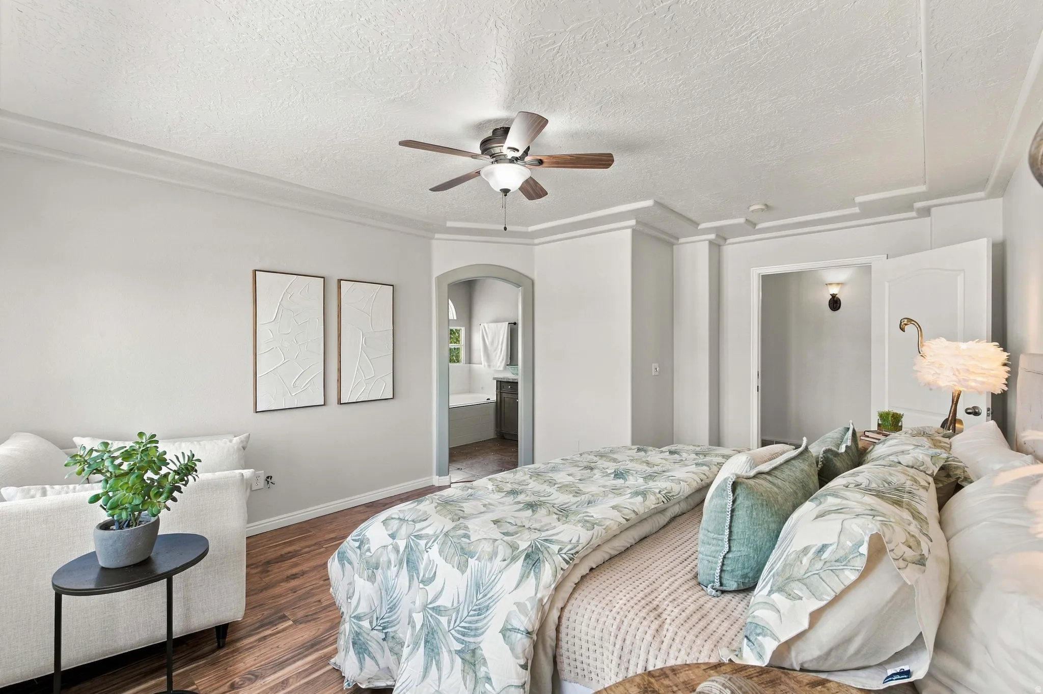 Large primary bedroom with recessed ceiling and arch leading to en suite bathroom.