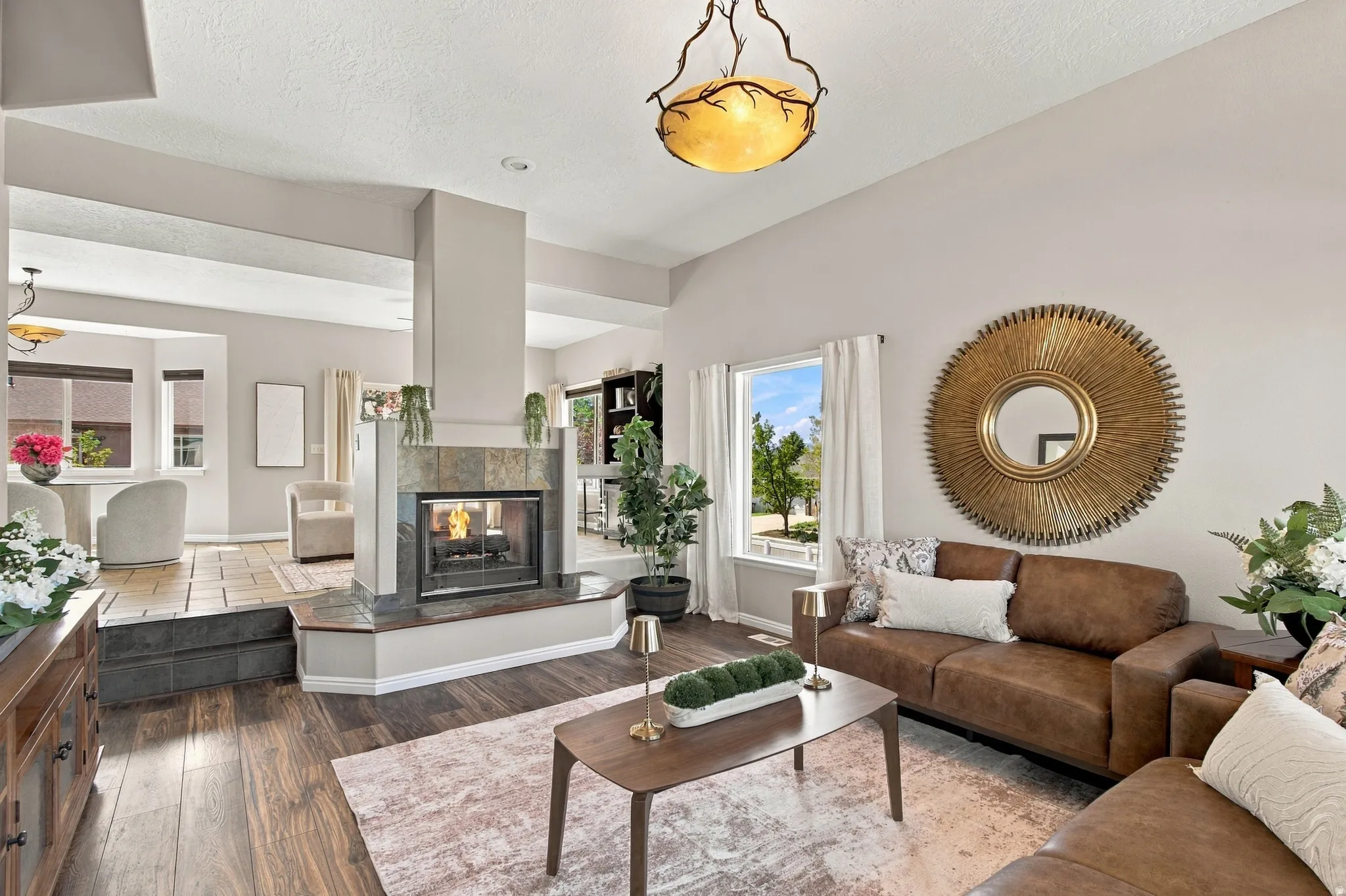 Open concept front living room with two sided gas fireplace opening to family room, dining and kitchen