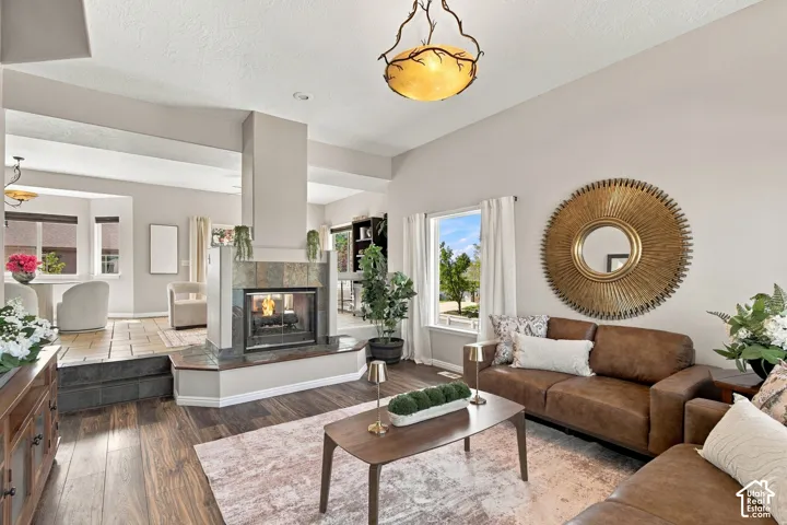 Open concept front living room with two sided gas fireplace opening to family room, dining and kitchen