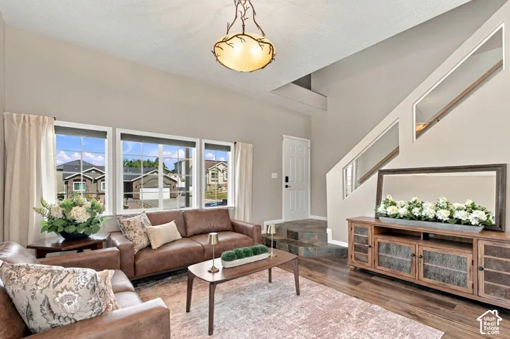 Living room with extra high ceilings, big windows with custom cellular shades, beautiful wood laminate and stone flooring.