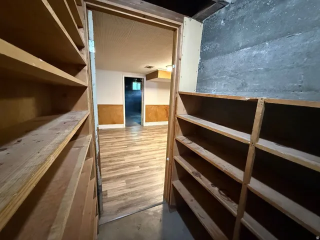 Built-in shelving units, wood-finish flooring, half-wall paneling, and an exposed concrete wall