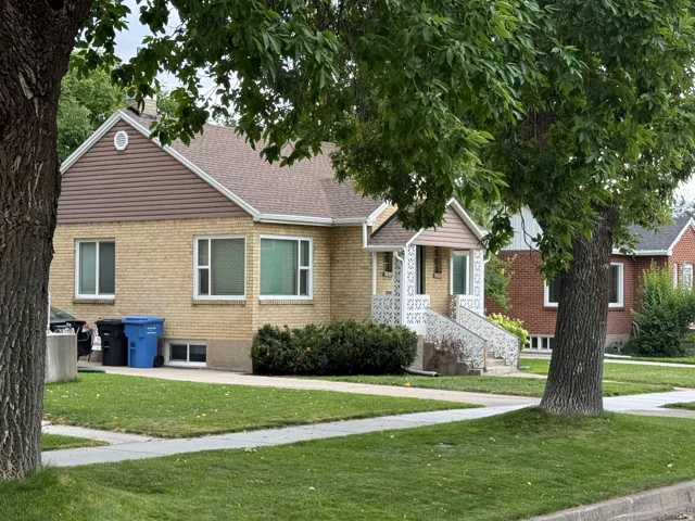 Brick exterior featuring brown siding accents, a covered front porch with decorative railings, and a peaked roof