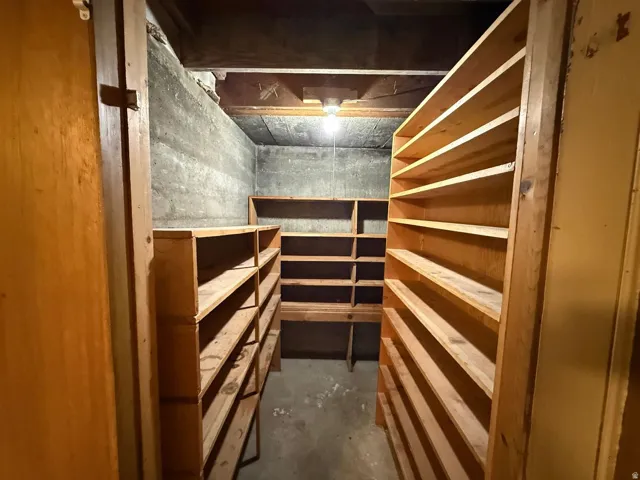 Expansive storage area featuring extensive wood shelving, concrete walls, and a concrete floor