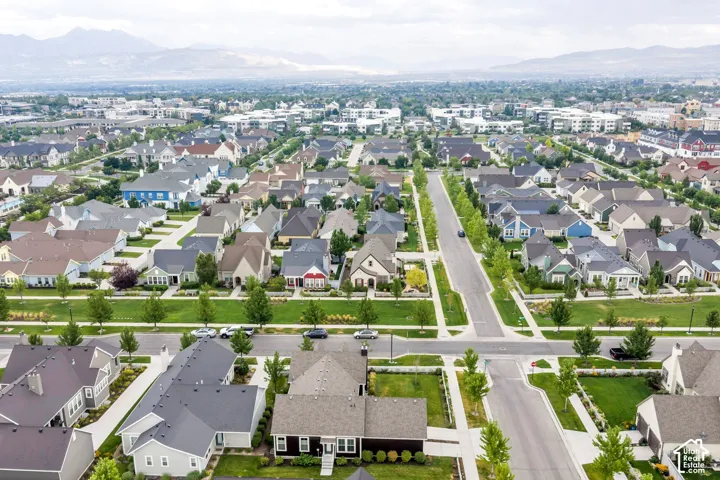 Expansive residential development featuring diverse architectural styles, tree-lined streets, and mountain scenery