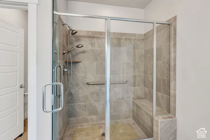 Glass-enclosed shower with a built-in bench, dual shower heads, and an integrated grab bar