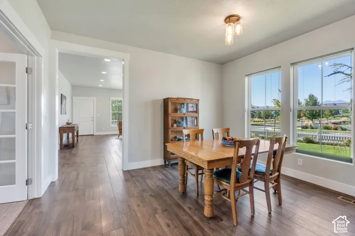 Dining area featuring two large windows, wood-finish flooring, a contemporary ceiling light fixture, and a doorway with French doors