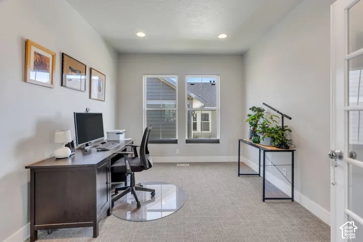 Recessed lighting, light gray wall color, two windows, textured carpeting, and French doors with glass panels