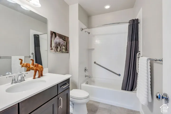 White subway tile shower surround with grab bar, built-in bathtub, dark wood-finish vanity with chrome hardware, white countertop with integrated sink, and large wall mirror