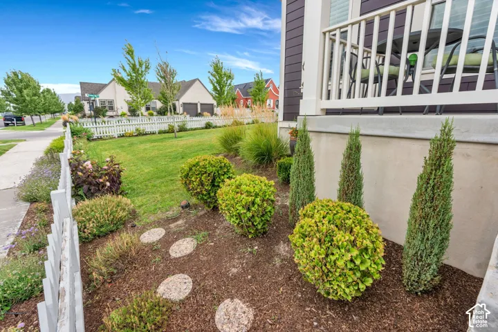 Front yard featuring a white picket fence, manicured lawn, and mature landscaping