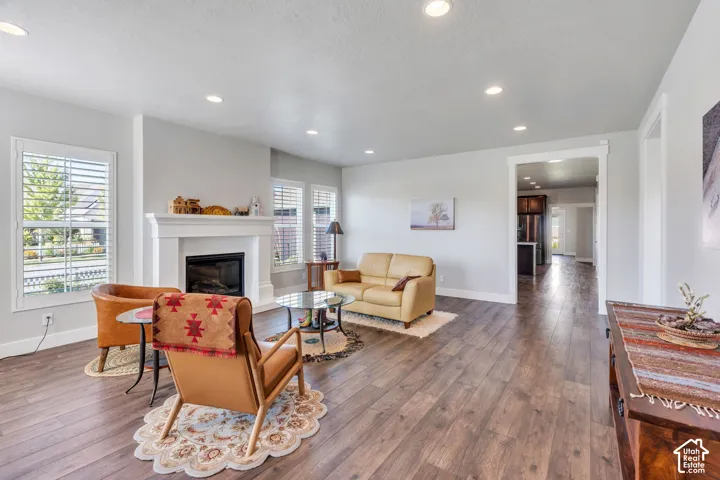 Recessed lighting, wood-finish flooring, white trim, and a fireplace with a mantel