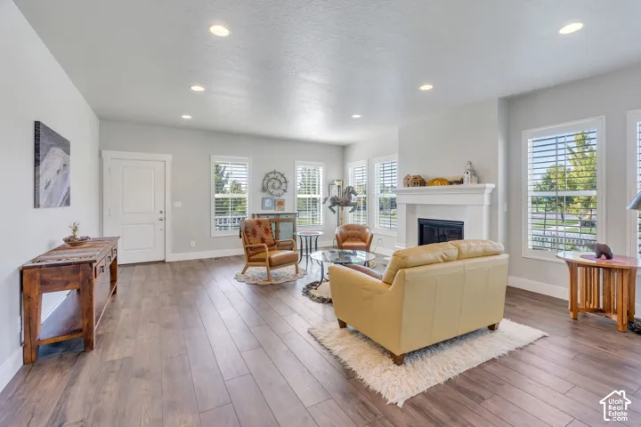 Spacious living area featuring wood-finish flooring, recessed lighting, and multiple windows with plantation shutters