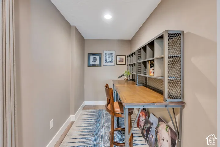 Built-in wood-finish desk with metal shelving, recessed lighting, and wood-finish flooring