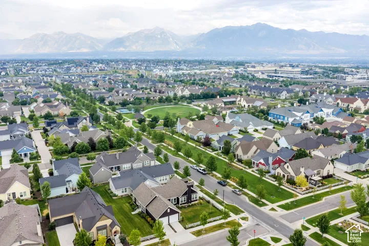 Expansive residential neighborhood with varied architectural styles, tree-lined streets, landscaped green spaces, and mountain backdrop