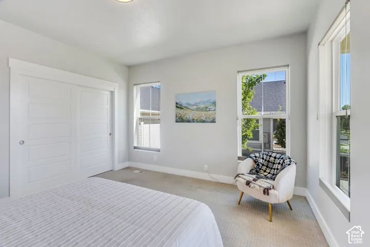 Carpeted room featuring dual sliding closet doors, multiple windows, and recessed lighting