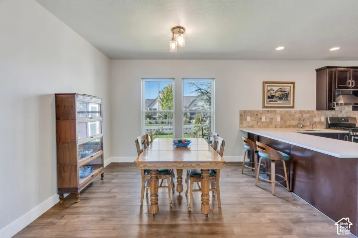 Expansive wood-finish flooring extending into the kitchen, featuring a peninsula with countertop seating and dark wood cabinetry