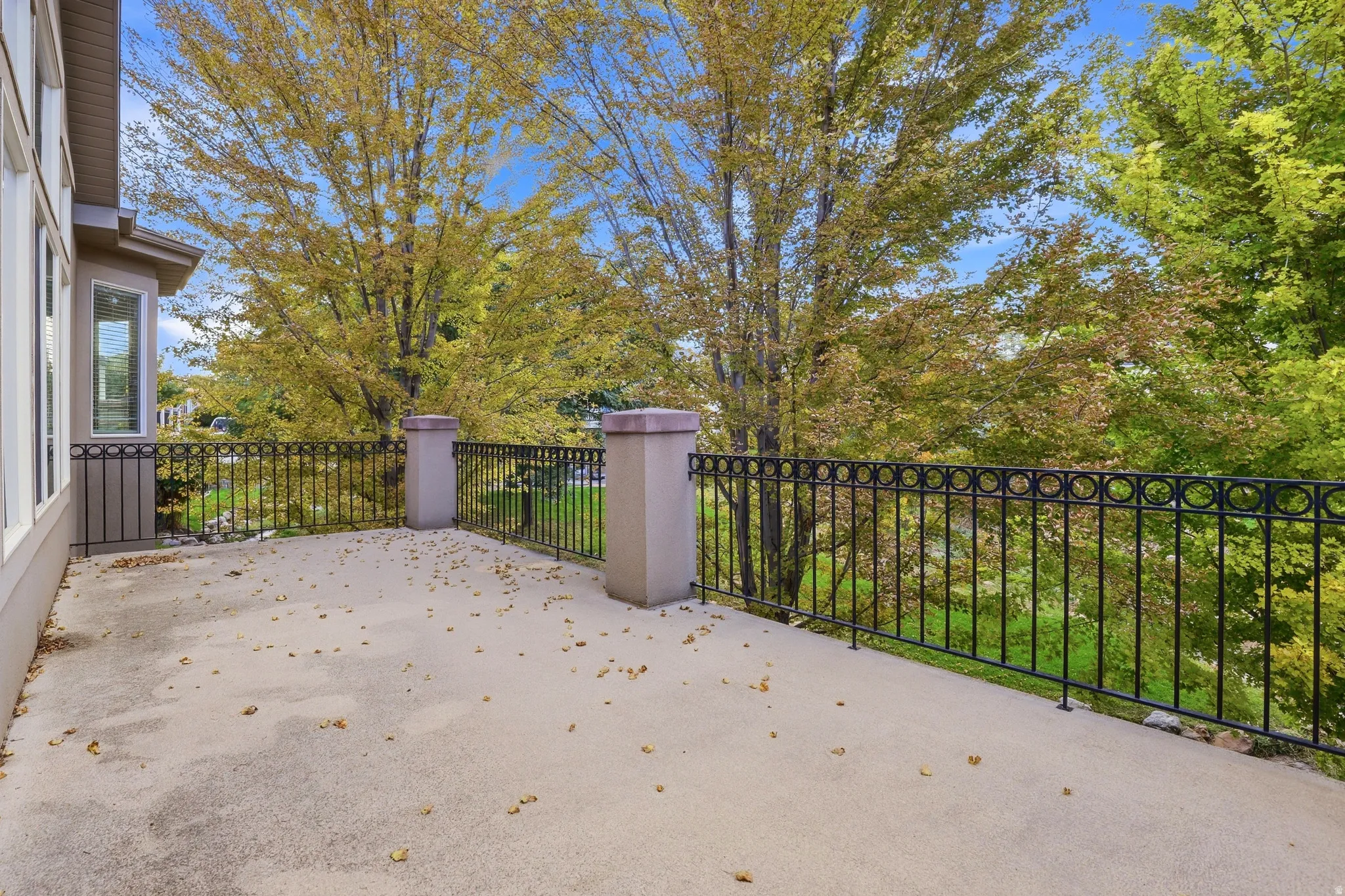 Spacious outdoor patio with decorative metal railing and robust pillar accents