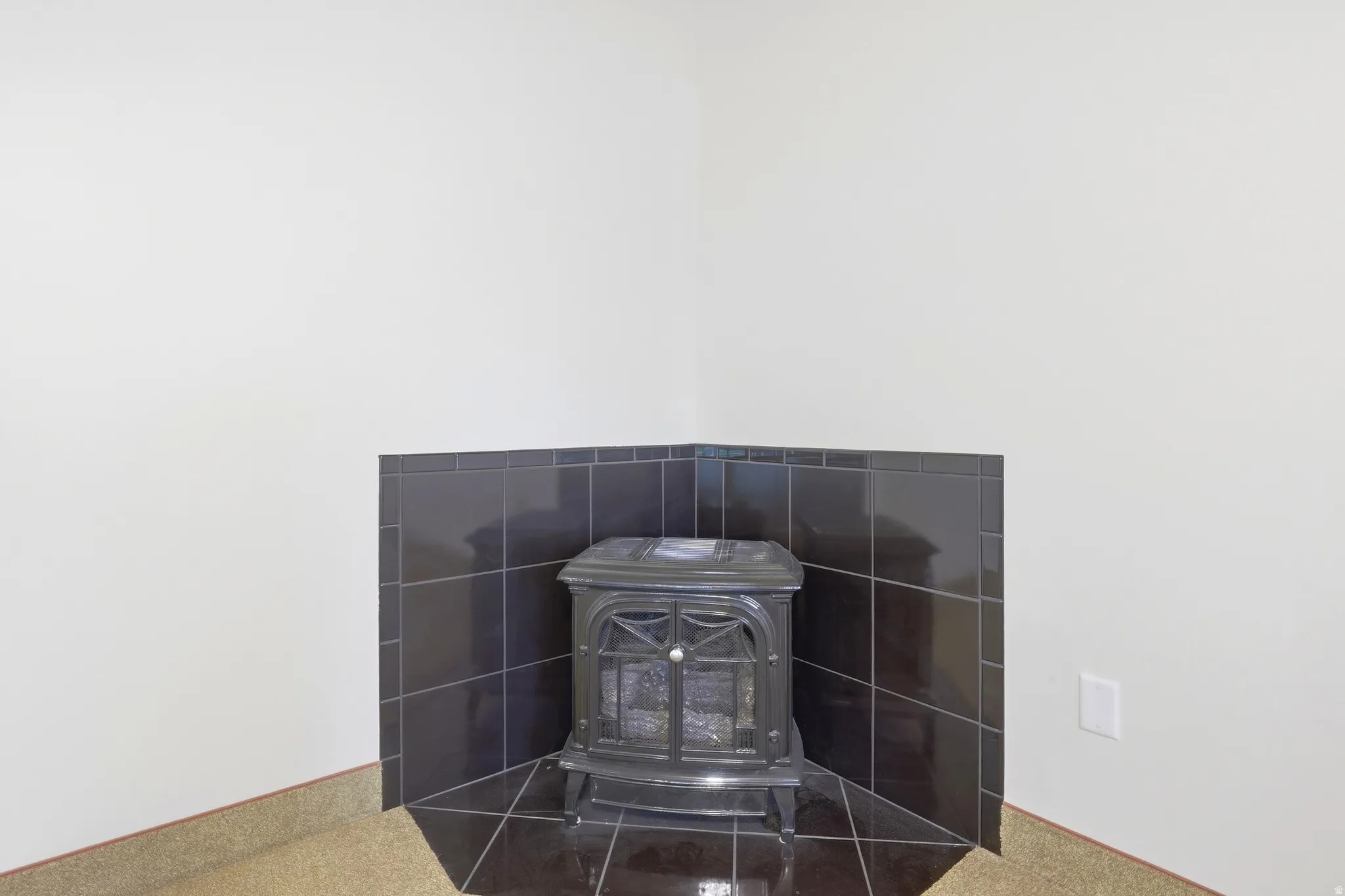 Corner wood-burning stove with a black tile surround
