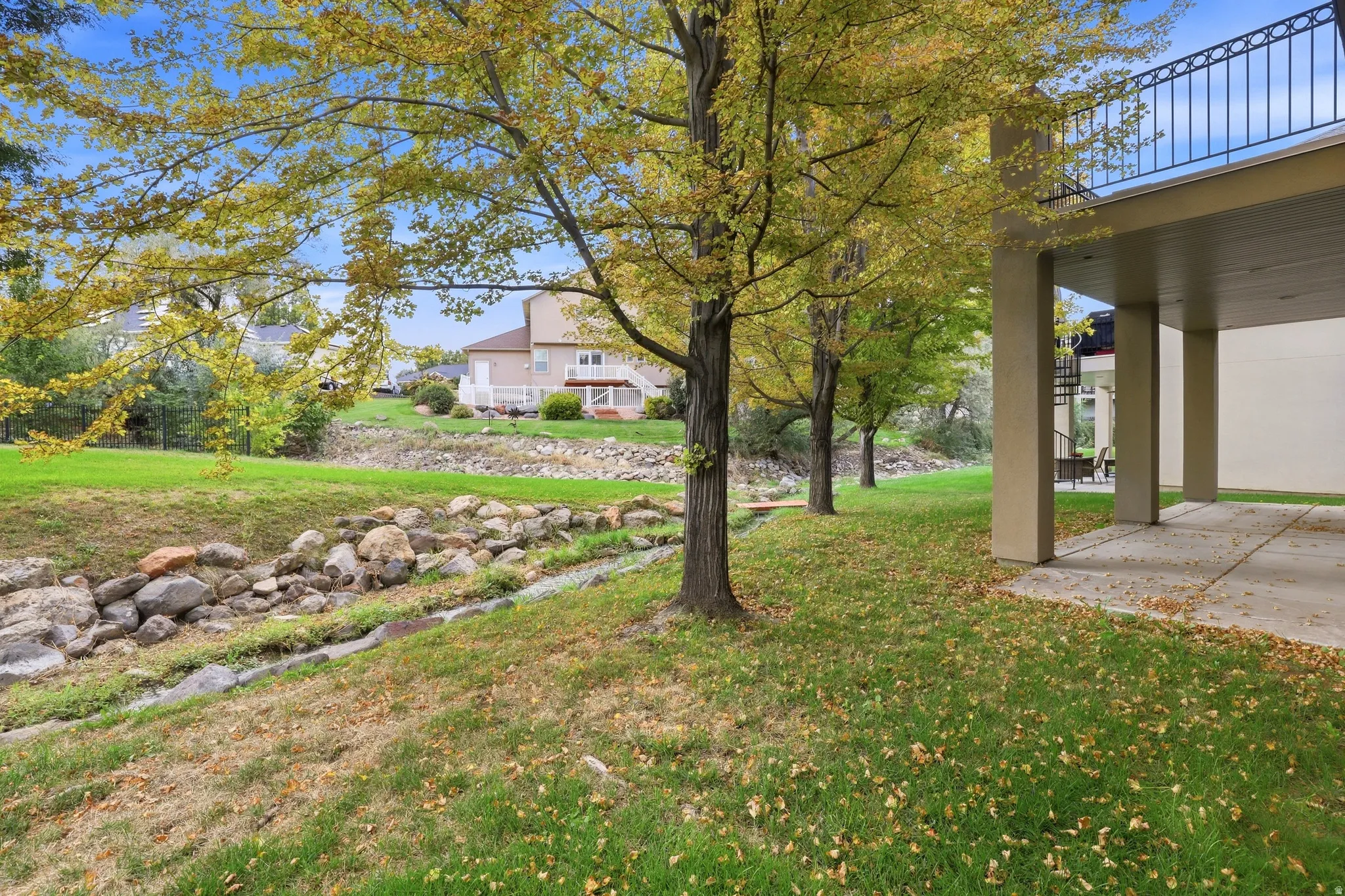Expansive lawn area with mature trees, featuring a rock-lined stream bed