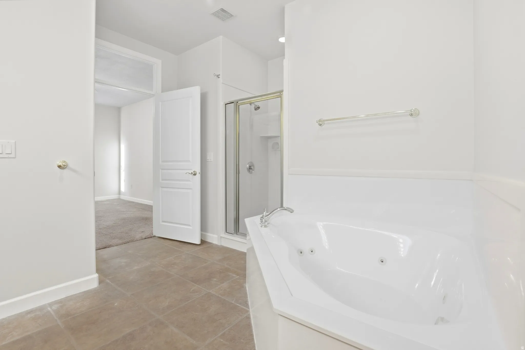 Soaking tub with integrated jets, glass-enclosed shower, and tile flooring