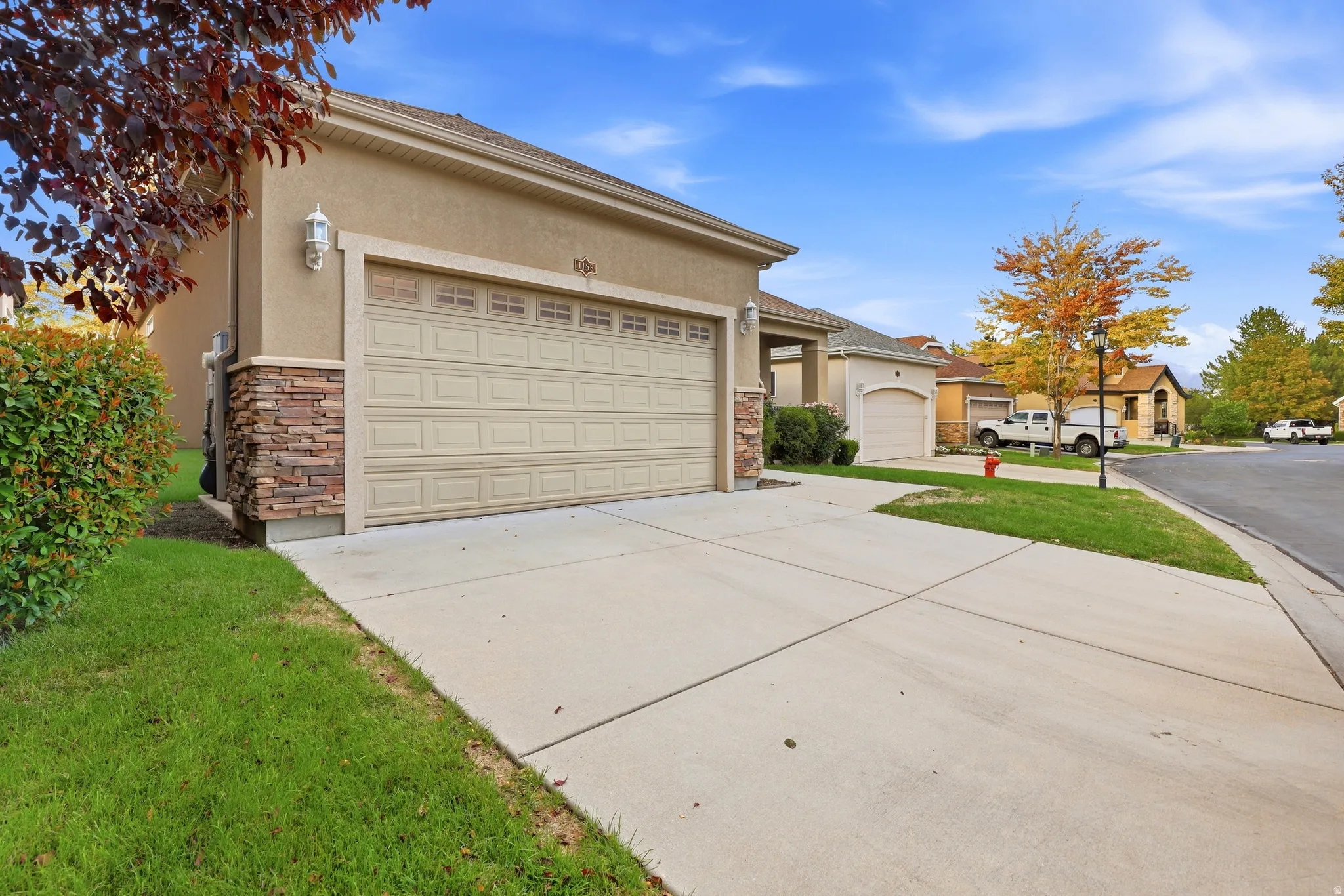 Stucco exterior with stone accenting, two-car garage, concrete driveway, and established front landscaping
