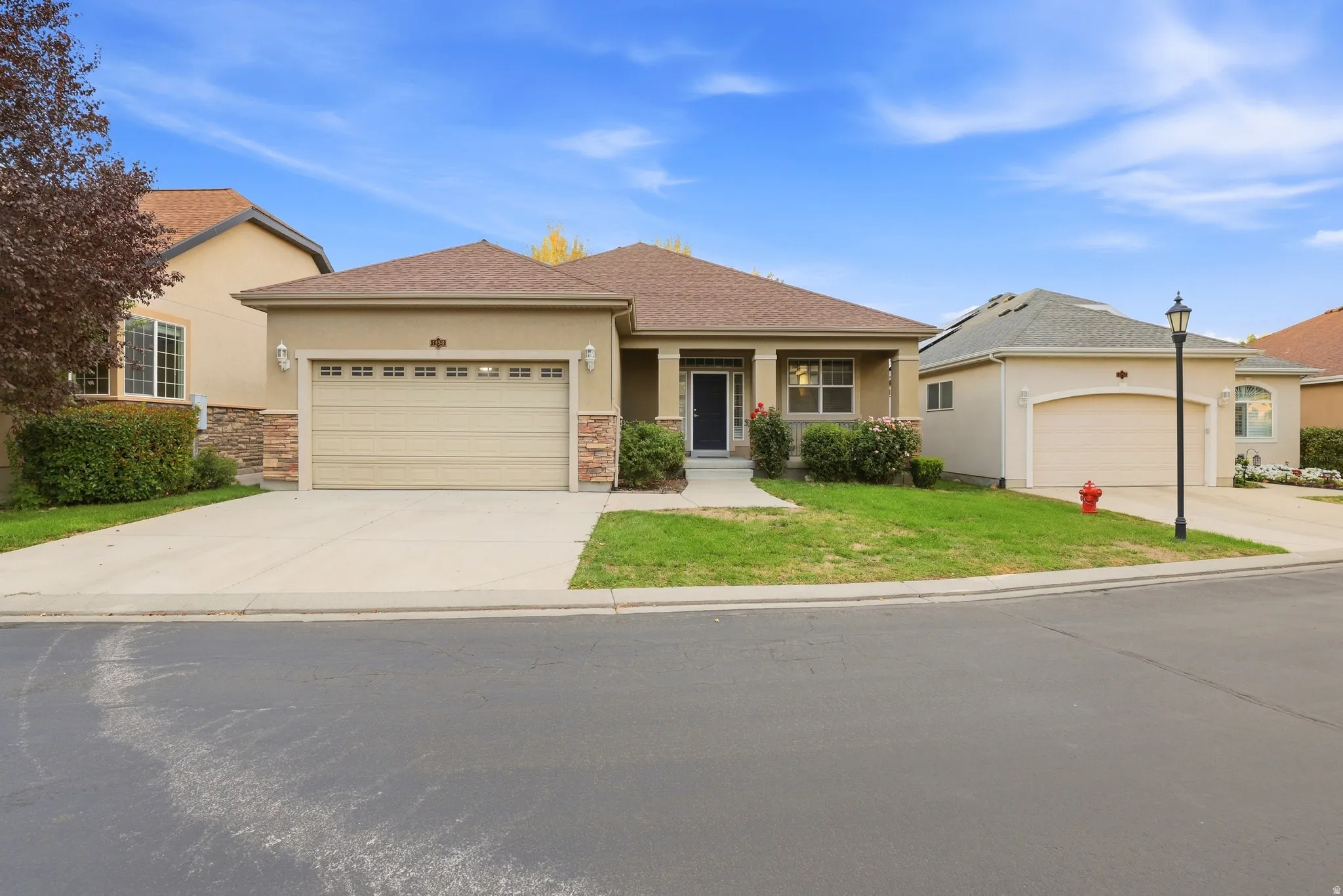 Stucco exterior with stone accents, attached garage, and concrete driveway