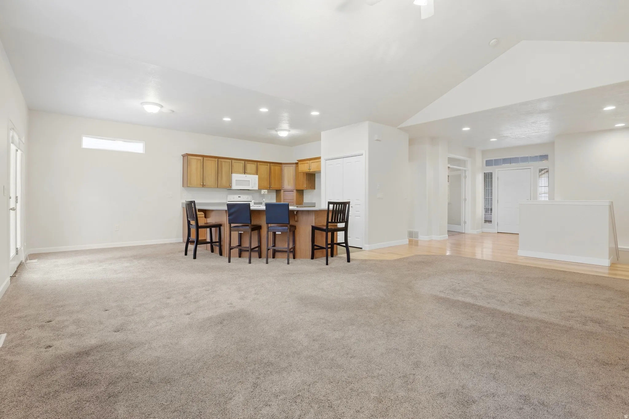 Recessed lighting, wood-finish cabinetry, white kitchen appliances, light wood-finish flooring, and vaulted ceiling