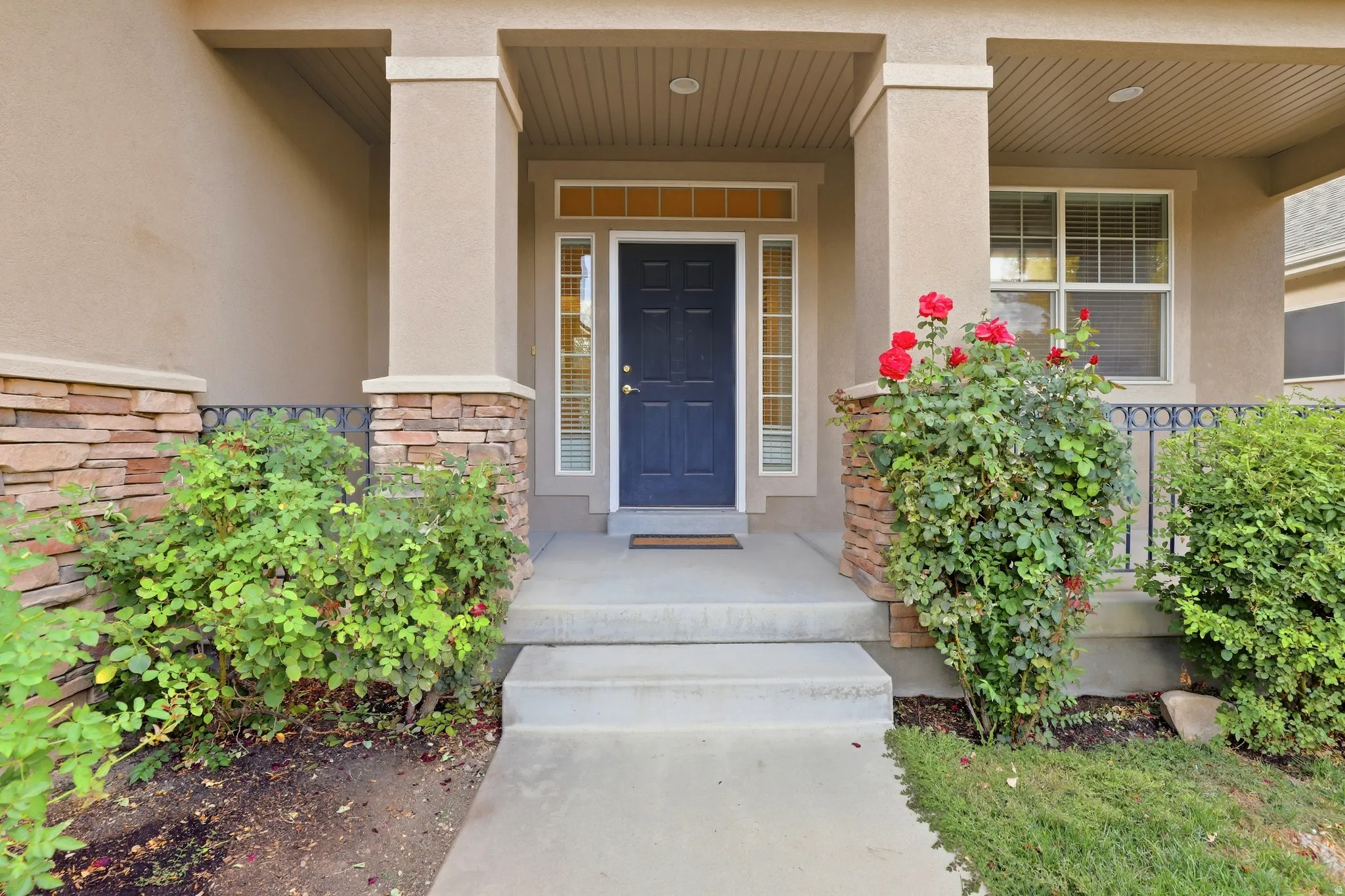 Covered entry with stone veneer accents and a dark blue front door