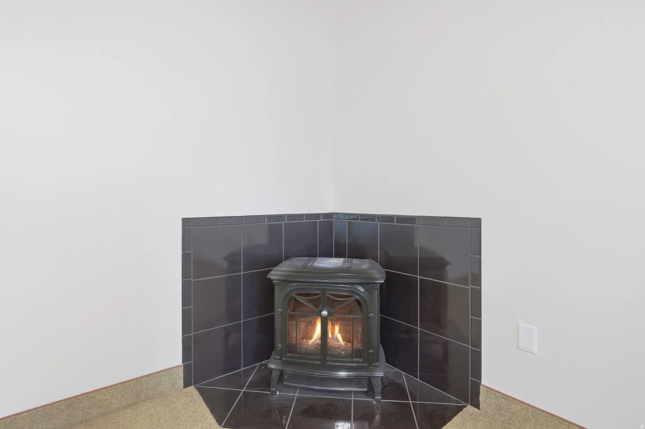 Corner wood-burning stove with a dark tile surround and hearth