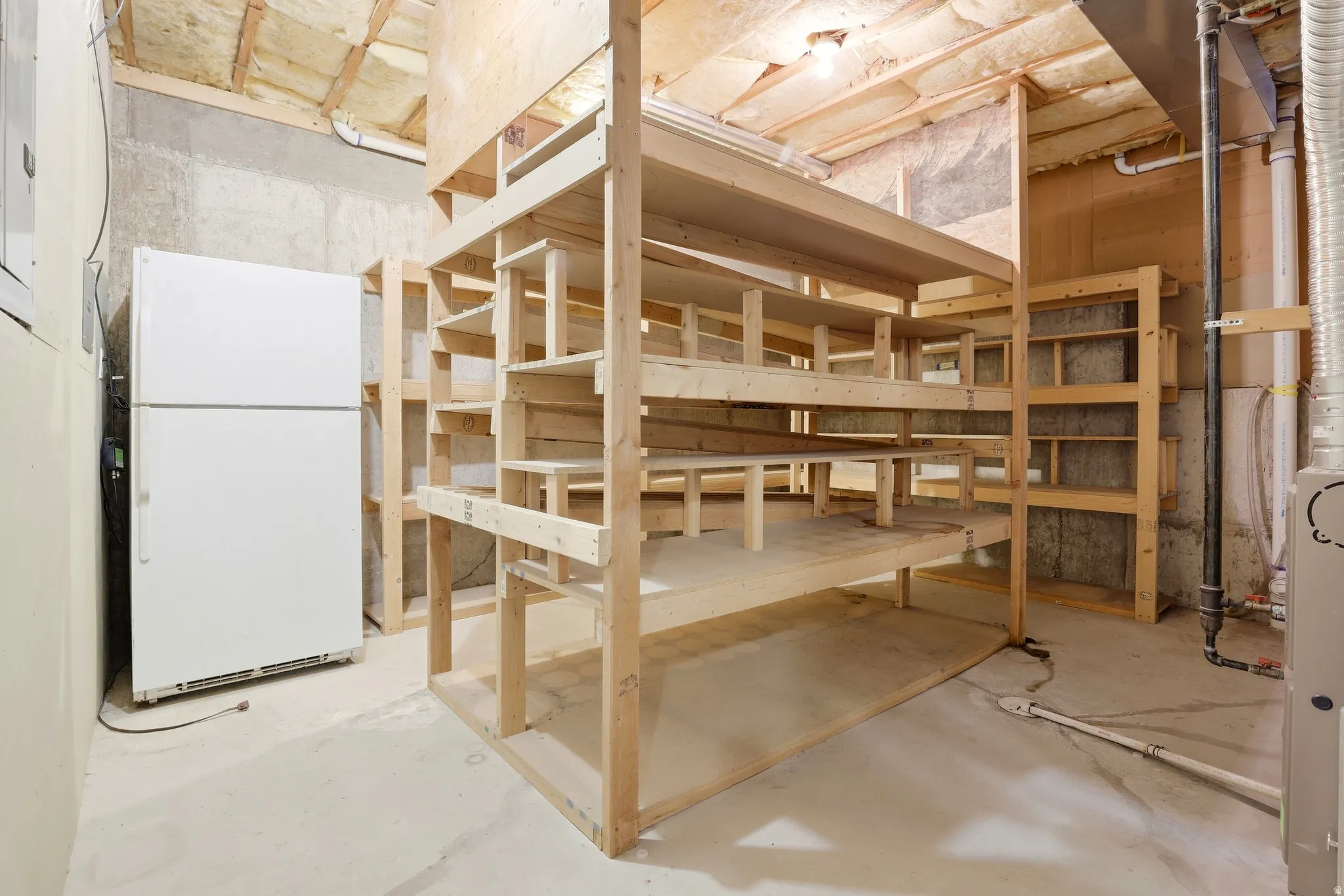 Expansive storage area with wood shelving units and exposed concrete walls