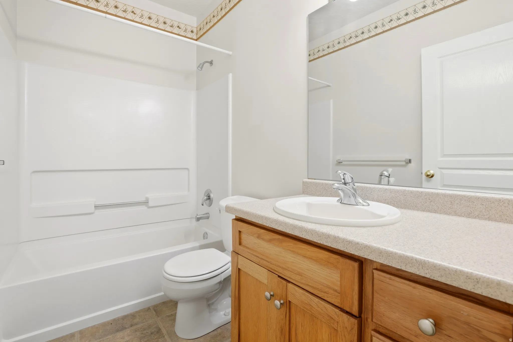 Bathroom featuring a full vanity with wood cabinetry, an integrated sink, and a spacious mirror
